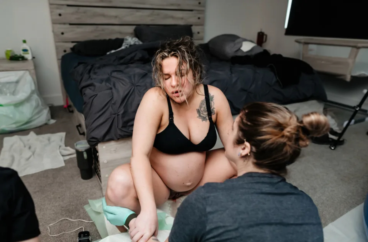 doula gently checking a newborn's weight during an in-home support visit